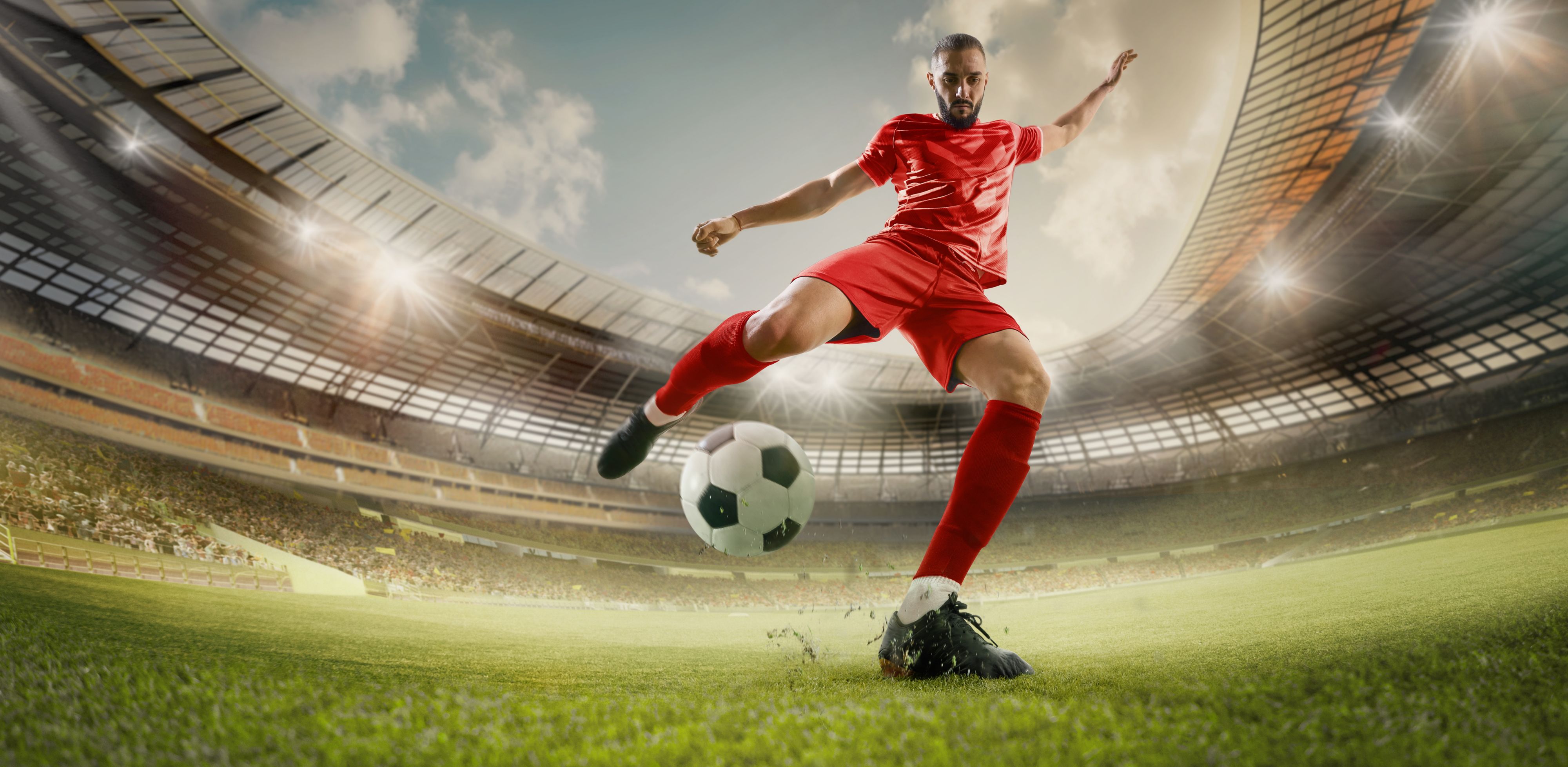 Soccer player kicking ball in red uniform